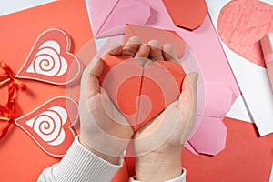 The child creates a hearts out of paper, hands close-up. Origami for Valentine& x27;s Day.