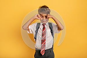 Child cries because does not want to go to school. Yellow background photo