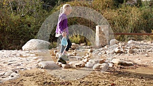 A child crosses a stream over stones without wetting his feet