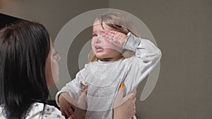 Child is crying in room in the arms of his mother. Mom calms child. Family mother and baby with tears in their eyes