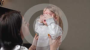 Child is crying in room in the arms of his mother. Mom calms child. Family mother and baby with tears in their eyes