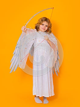 Child cupid hold bow and arrow. Kid wearing angel costume white dress and feather wings. Innocent child.