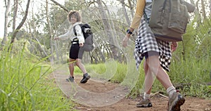 Child with curly hair is walking on a dirt path, smiling towards the camera