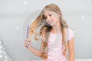 Child curly hairstyle hold hairbrush or comb. Apply oil before combing hair. Healthy hair. Conditioner or mask organic