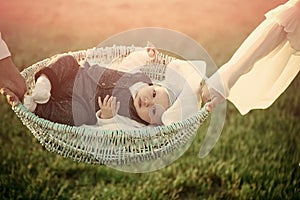 Child custody. Infant lie in basket held in hands on green grass