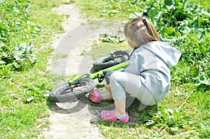 Child cute little girl fell off her bike in forest