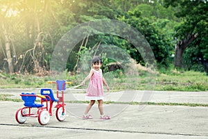 Child cute little girl having fun to pull her tricycle