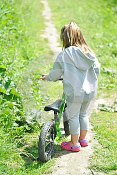 Child cute little girl riding bike in forest