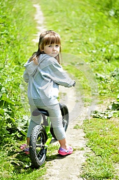 Child cute little girl riding bike in forest