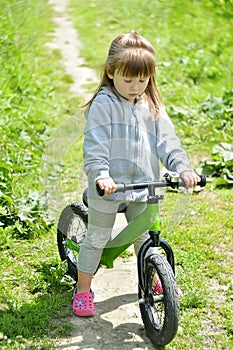 Child cute little girl riding bike in forest