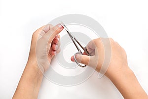 A child cuts his fingernails with manicure scissors at home. On a white background. Quarantine, isolation, independent