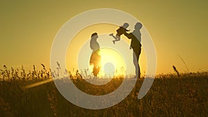 Child, dad and mom play in the meadow in the sun. concept of a happy childhood. mother, father and little daughter