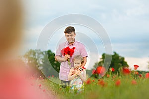 Child with dad picking flowers in poppy field