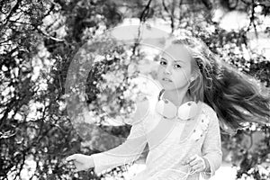 Child dance to music in summer park. Small girl enjoy music in headphones outdoor. Kid dancer with long flying hair