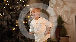 A child dances near a Christmas tree with a garland. Selective focus.