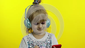 Child dances with smartphone, listening to music on headphones. Little kid girl dancing, having hun