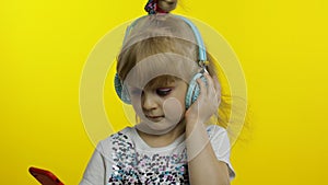 Child dances with smartphone, listening to music on headphones. Little kid girl dancing, having hun