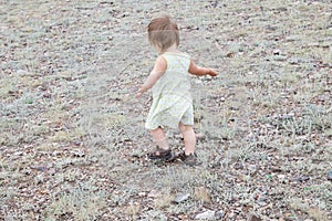 Child dancing outdoors. Little baby girl walking away. Running away little baby girl in steppe. Big landscape environment