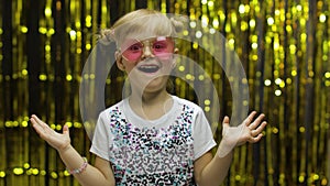 Child dancing, show amazement, fooling around, smiling. Girl posing on background with foil curtain