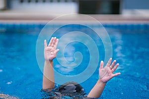 Child in danger drowning in the pool,  kid girl cannot swim to deep water and raise two hand for help on swimming pool