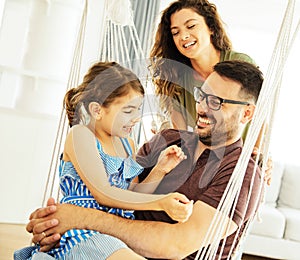 child daughter family happy mother father sofa playing fun together girl cheerful smiling home indoor swing