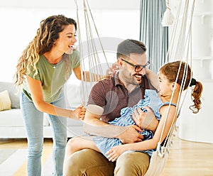 child daughter family happy mother father sofa playing fun together girl cheerful smiling home indoor swing