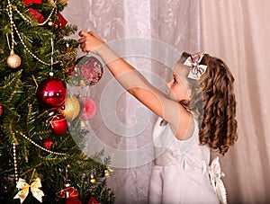 Child decorate on Christmas tree.