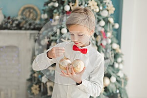 Child decorating Christmas tree at home. Boy hangs Christmas balls on tree. Christmas Eve concept