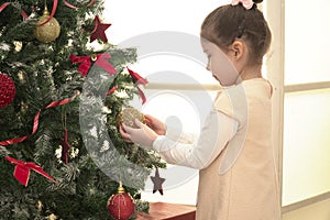 Child decorating Xmas tree in family living room