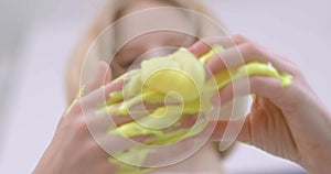 Child delightfully playing with homemade yellow slime, stretches slime to the sides, an engaging sensory activity