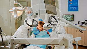 Child on dental chair in dentist surgery treated with dental drill