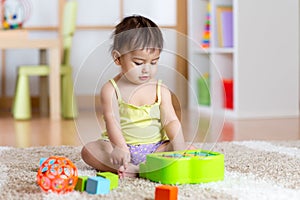 Child with develepmental toys. Early education for kids. Colorful wooden art toys. Little girl play music. Kid with