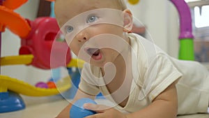 Child development, cheerful cute baby crawling on floor and laughing close-up