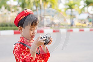 Child with digital compact camera outdoors. Cute little Vietnamese boy in ao dai dress smiling. Tet holiday