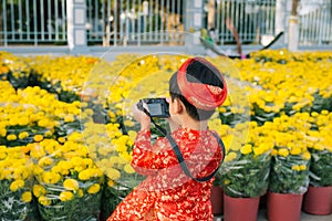 Child with digital compact camera outdoors. Cute little Vietnamese boy in ao dai dress. Tet holiday
