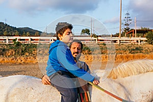 Child with disabilities having an equine assisted therapy with a physiotherapist.