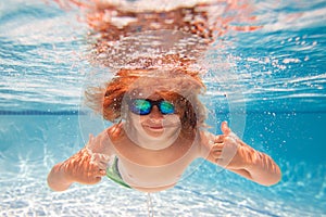 Child dives into the water in swimming pool. little kid swim underwater in pool. Child swimming underwater in sea or