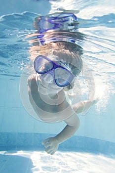 Child diving undwerwater in mask in pool