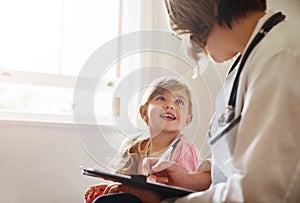 Child doctor, girl and talking trust with medical checklist in a hospital for wellness and health. Happiness, clinic