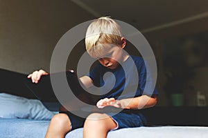 Child does homework , lying in bed using his laptop or skyping.