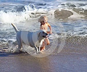 Child, dog and beach with kid playing with pet animal running on sand by the ocean. Holiday, children and dogs swimming