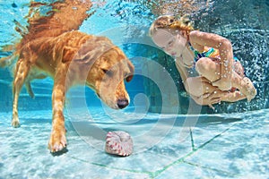 Child with dog dive underwater in swimming pool