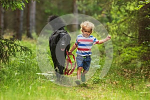 Child and dog,little boy running with black hovie alone forest path