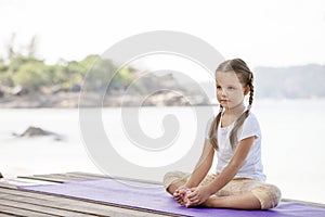 Child doing exercise on platform outdoors. Healthy lifestyle. Yoga girl