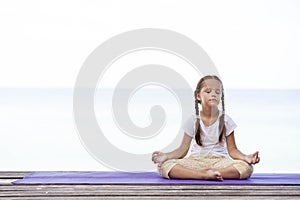 Child doing exercise on platform outdoors. Healthy lifestyle. Yoga girl