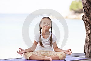 Child doing exercise on platform outdoors. Healthy lifestyle. Yoga girl