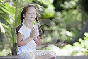 Child doing exercise on platform outdoors. Healthy lifestyle. Yoga girl