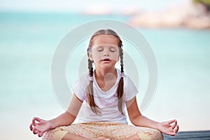 Child doing exercise on platform outdoors. Healthy lifestyle. Yoga girl