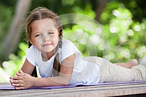 Child doing exercise on platform outdoors. Healthy lifestyle. Yoga girl