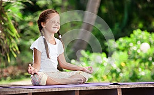 Child doing exercise on platform outdoors. Healthy lifestyle. Yoga girl